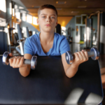 Young person holding weights in local centre gym