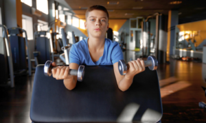 Young person holding weights in local centre gym
